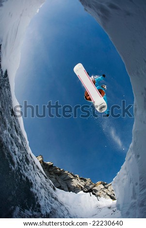 View from below of agile snowboarder in high jump over blue sky