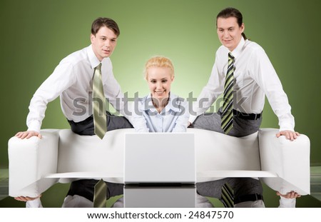 Photo of attractive woman typing on laptop with two men sitting behind her