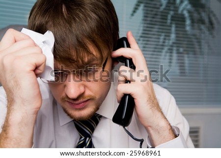 Portrait of frustrated employer calling on the phone and holding crumpled paper in hand