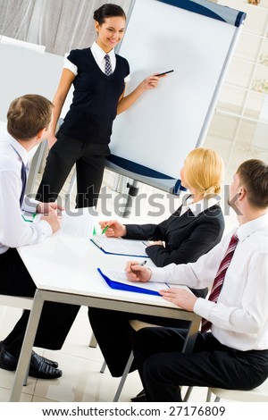 Image of several listeners looking attentively at young consultant pointing at board