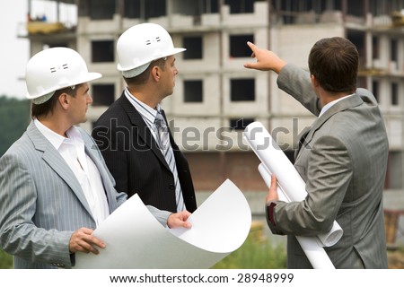 Image of three workers looking construction during discussion of architectural project