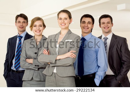 Portrait of successful businesswoman smiling at camera with several employees standing next to her