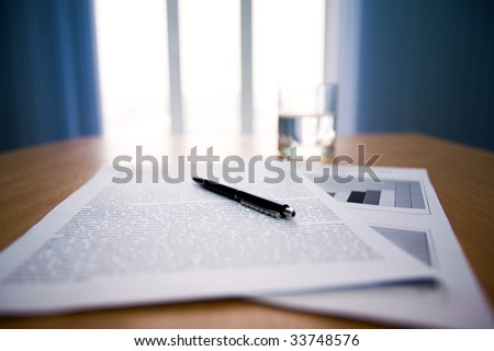 Image of workplace with focus on papers and pen on the table