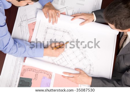 Above view of engineers over blueprints during work planning
