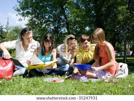 Portrait of busy students reading books in park together