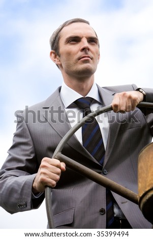 Portrait of powerful businessman holding steer and looking forwards on white background