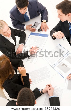 Above view of young co-workers working with papers and consulting each other