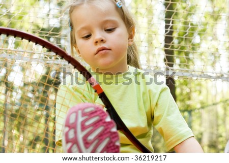 Nice girl with tennis racket looking at it outdoors during vacation