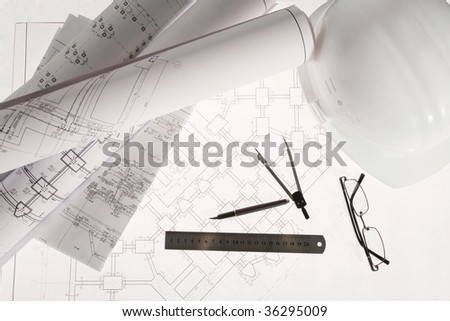 Close-up of blueprints with sketches of projects, eyeglasses, helmet and some mechanical tools
