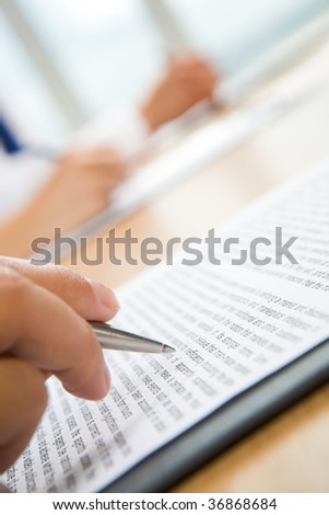 Vertical image of human hand holding pen and making notes