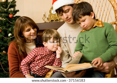 Portrait of friendly family looking into interesting book on Christmas day