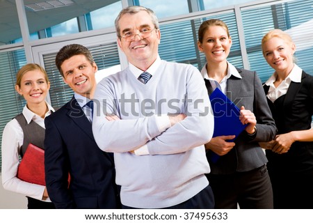 Image of senior leader smiling at camera with several employees behind