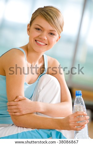 Portrait of lovely girl holding bottle of water in hand and smiling