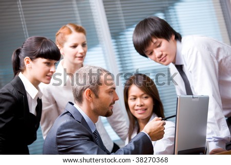 Portrait of executive employees looking at laptop monitor in office and interacting