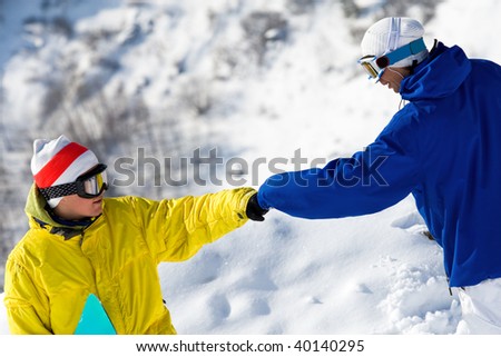 Portrait of two guys with snowboards climbing down snow-covered mountain