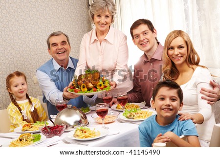 Portrait of big family sitting at festive table and looking at camera with smiles