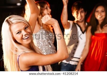 Portrait of cheerful girl dancing at party with her friends behind