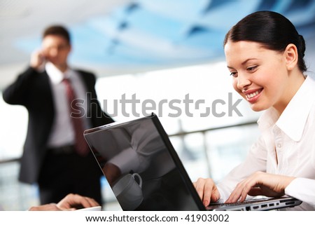 Portrait of executive employee working with laptop on background of calling man