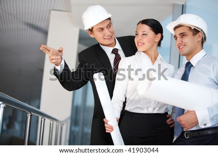 Image of group of three workers looking somewhere while interacting with each other