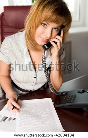 Portrait of lovely business lady calling by the phone in office and looking at camera