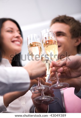 Close-up of human hands cheering up with flutes of golden champagne