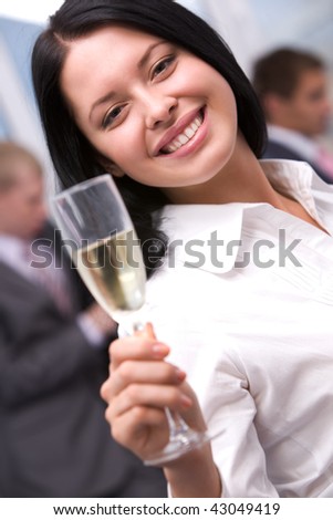 Portrait of beautiful female stretching flute with champagne and smiling at camera