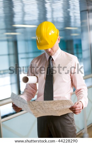 Portrait of confident foreman in helmet learning blueprint