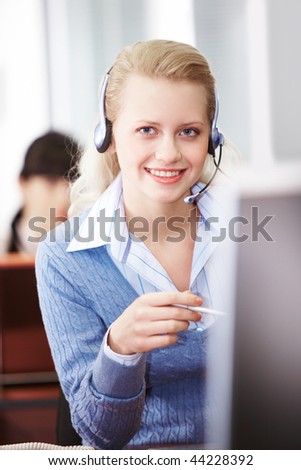 Pretty secretary speaking on headphone in the office
