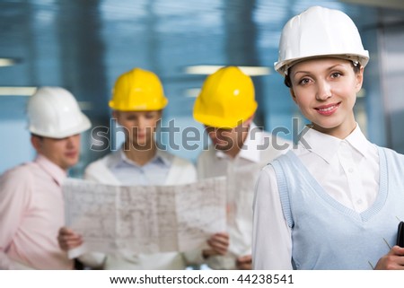 Portrait of confident woman in helmet looking at camera in working environment