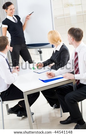 Image of several listeners looking attentively at young consultant pointing at board