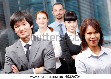 Photo of successful business partners looking at camera with co-workers behind them