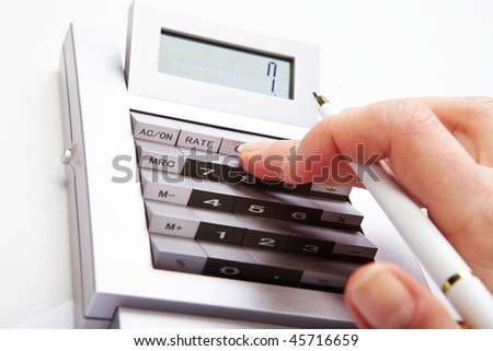 Photo of female hand with pen over calculator keys pushing them during work