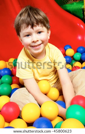 Happy lad looking at camera while sitting in balls