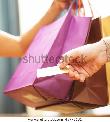 Vertical image of man?s hand passing over credit card to shop assistant after shopping