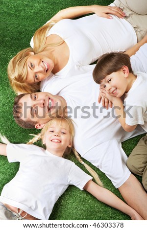 Above view of family members lying on green grass and smiling at camera
