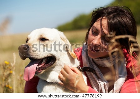 Close-up of dog with tongue hanging out and woman embracing its