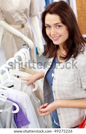 Portrait of pretty woman choosing new tanktop and looking at camera in clothing department