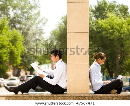 Image of two business partners sitting outside and working