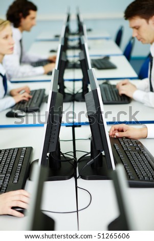 Business people sit at the tables with monitors on its in line