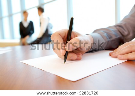 Close-up of male hand with pen over paper during conference