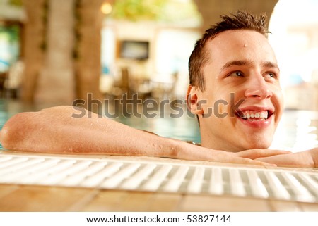 Portrait of happy guy laughing in swimming pool