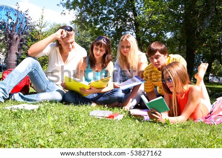Portrait of smart friends reading books in park together