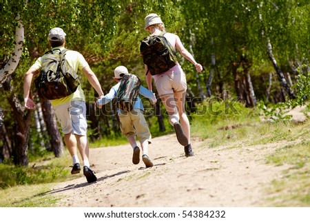 Rear view of dynamic family members running down country road at summer