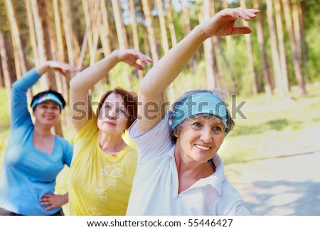 Portrait of aged women with their arms raised while doing physical exercise