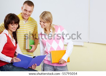 Portrait of smart students looking at textbook in girl?s hands and reading it