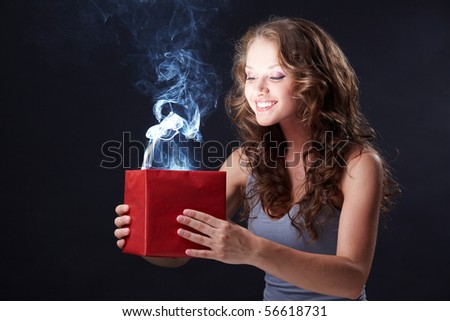 Image of happy girl looking into open gift box and wondering