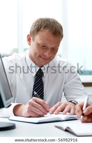 Portrait of businessman writing in notepad during work planning in office