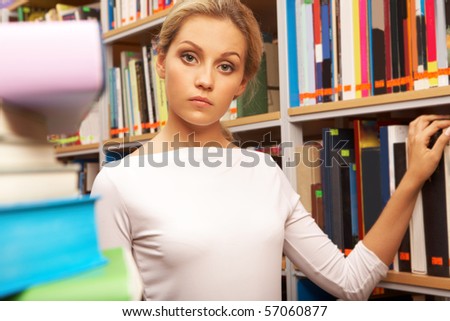Image of smart student standing in aisle and looking at camera in library
