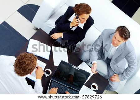 Image of company of successful partners discussing business plan at meeting