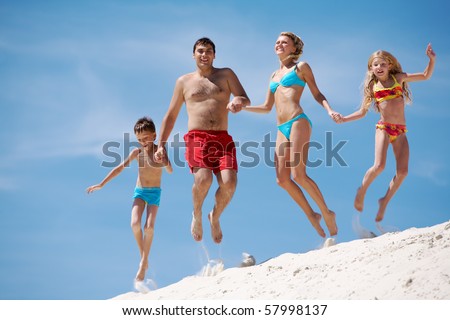 Photo of happy family jumping on sand on summer vacation